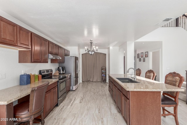 kitchen with sink, an island with sink, a kitchen breakfast bar, and appliances with stainless steel finishes