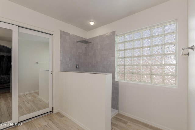 bathroom with tiled shower and wood-type flooring