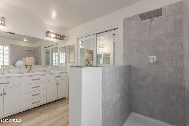 bathroom with a tile shower, hardwood / wood-style flooring, and vanity