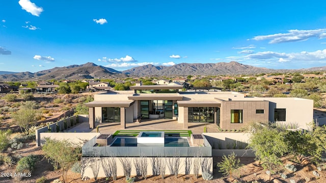 rear view of house with a mountain view, a swimming pool with hot tub, and a patio