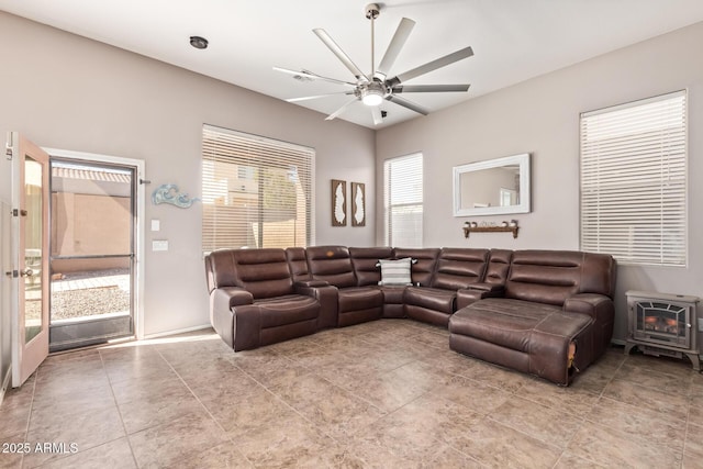 living room with ceiling fan, light tile patterned floors, and a wood stove