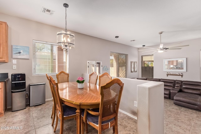 dining area with ceiling fan with notable chandelier, a wealth of natural light, and light tile patterned flooring