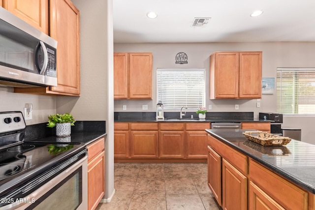 kitchen featuring appliances with stainless steel finishes, sink, and dark stone counters