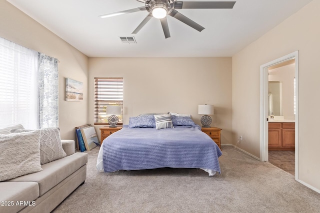 bedroom with light carpet, ensuite bath, and ceiling fan