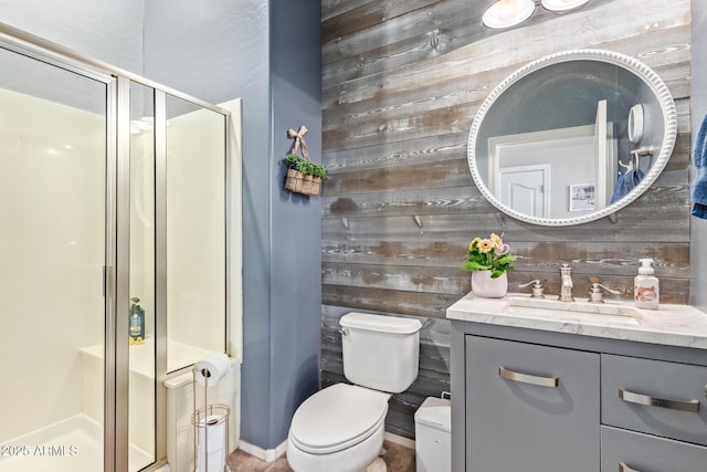 bathroom featuring vanity, wooden walls, a shower with door, and toilet