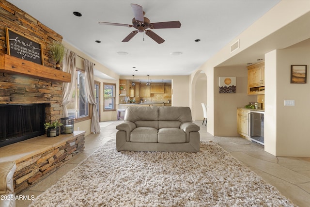 living room featuring a fireplace, ceiling fan, and wine cooler