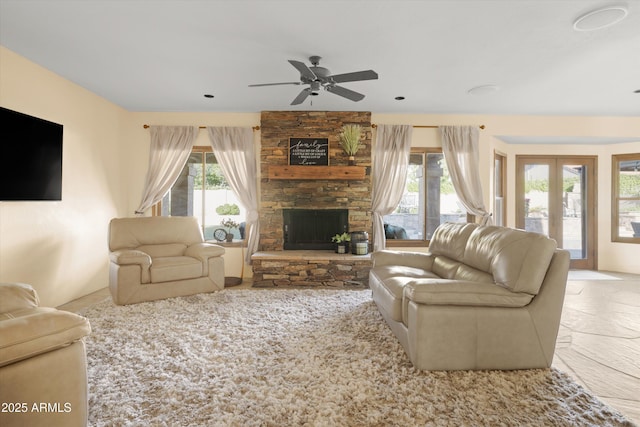 living room with a fireplace, french doors, and ceiling fan