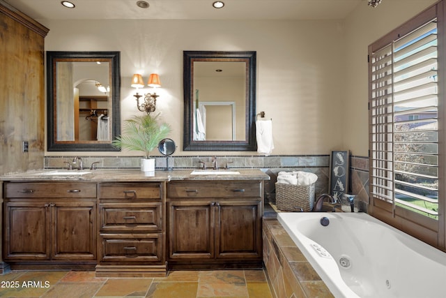 bathroom with vanity, a relaxing tiled tub, and a wealth of natural light