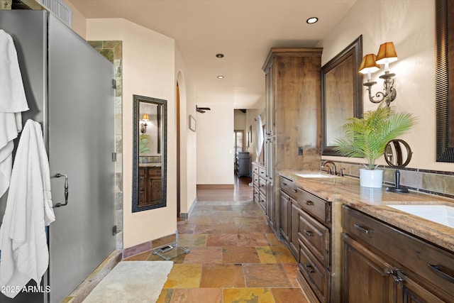 bathroom featuring a shower with door and vanity