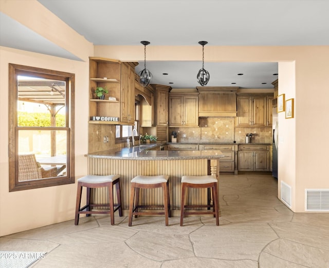 kitchen featuring a breakfast bar area, kitchen peninsula, premium range hood, pendant lighting, and tasteful backsplash