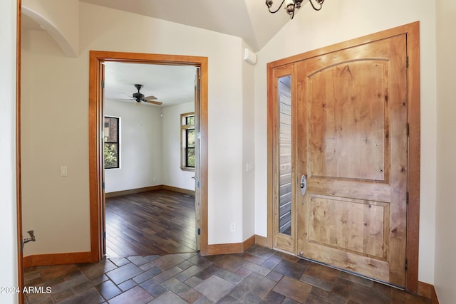 foyer entrance with ceiling fan with notable chandelier, dark hardwood / wood-style flooring, and lofted ceiling