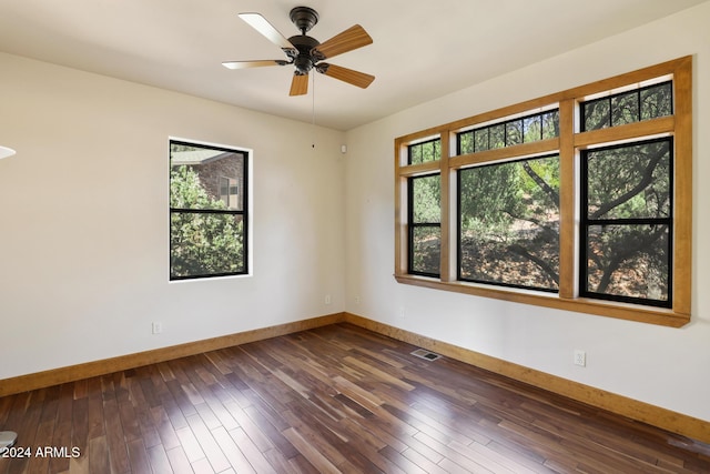 spare room featuring ceiling fan, a healthy amount of sunlight, and dark wood-type flooring