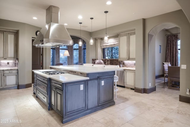 kitchen featuring hanging light fixtures, backsplash, island exhaust hood, a kitchen island, and stainless steel gas cooktop