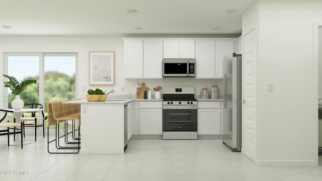 kitchen featuring stainless steel appliances, white cabinetry, light tile patterned floors, and a kitchen breakfast bar