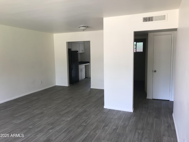 empty room with baseboards, dark wood-type flooring, and visible vents