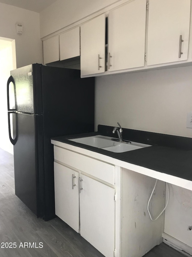 kitchen featuring freestanding refrigerator, white cabinetry, dark wood-style flooring, and a sink