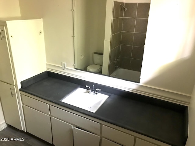 bathroom with toilet, wood finished floors, vanity, and shower / bath combination
