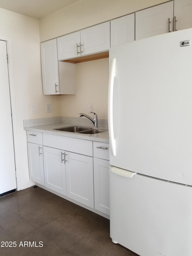 kitchen featuring a sink, freestanding refrigerator, light countertops, and white cabinets