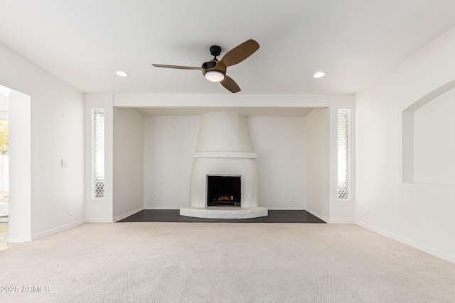 unfurnished living room with ceiling fan, carpet flooring, and a large fireplace