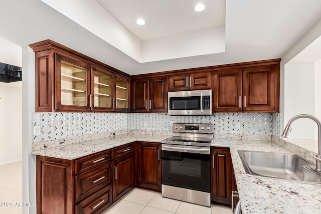 kitchen with light stone counters, sink, light tile patterned floors, and stainless steel appliances