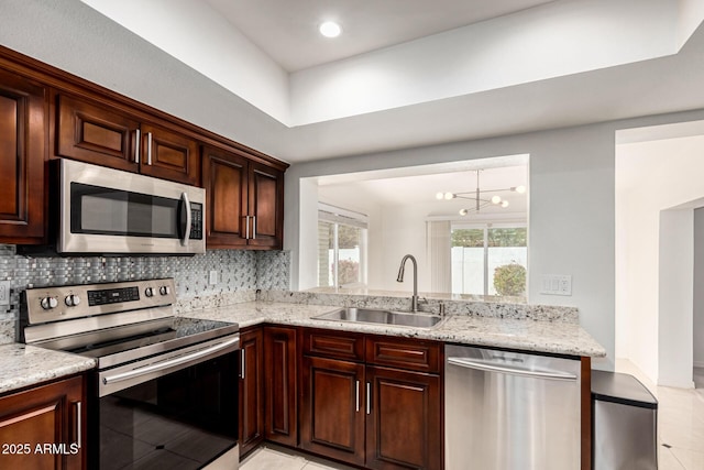 kitchen with stainless steel appliances, tasteful backsplash, sink, light stone counters, and light tile patterned floors