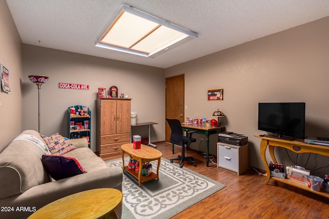 living room with wood-type flooring, a textured ceiling, and a skylight