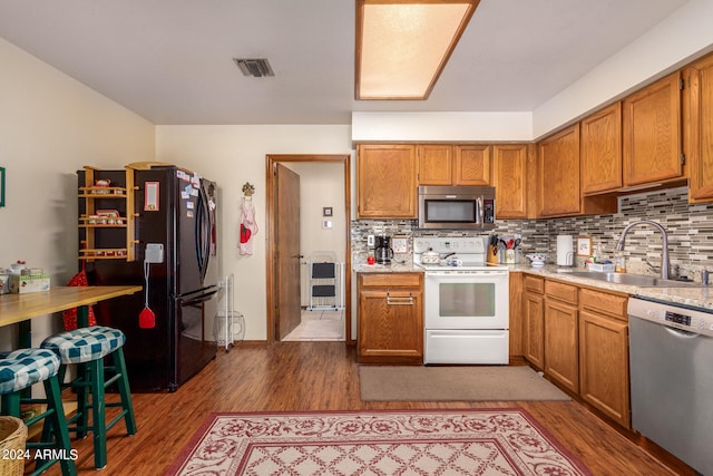 kitchen featuring dark hardwood / wood-style flooring, appliances with stainless steel finishes, backsplash, and sink