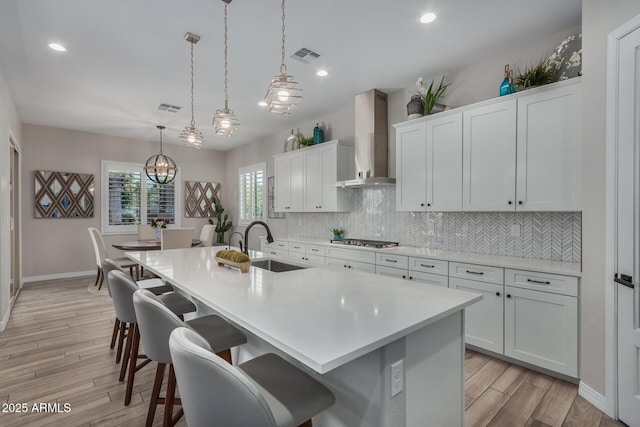14571 W Wethersfield Rd, Surprise, AZ 85379 - kitchen with wall chimney exhaust hood, stainless steel gas cooktop, a sink, backsplash, and a center island with sink
