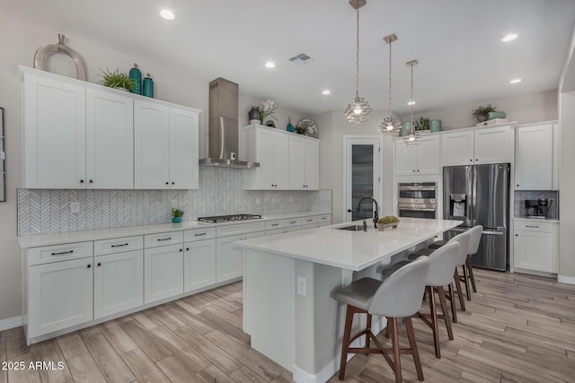 14571 W Wethersfield Rd, Surprise, AZ 85379 - kitchen with appliances with stainless steel finishes, wall chimney exhaust hood, a sink, backsplash, and light wood finished floors