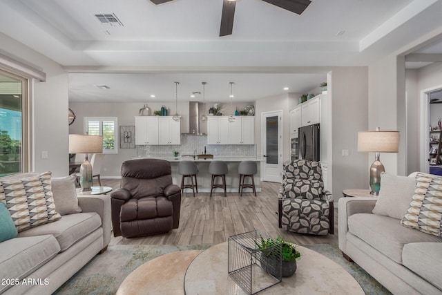 14571 W Wethersfield Rd, Surprise, AZ 85379 - living area with light wood finished floors, a ceiling fan, and a tray ceiling
