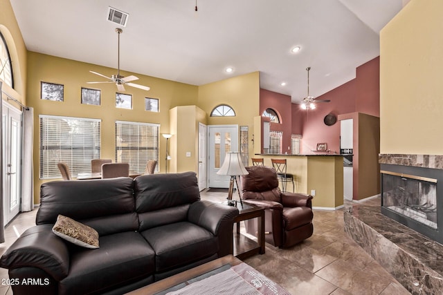 living room featuring ceiling fan, high vaulted ceiling, a high end fireplace, recessed lighting, and baseboards