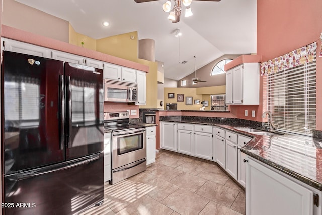kitchen featuring appliances with stainless steel finishes, a ceiling fan, a sink, vaulted ceiling, and white cabinetry