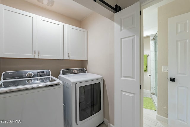 washroom featuring cabinets, washing machine and dryer, a barn door, and light tile patterned flooring