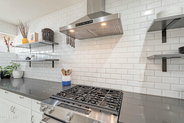 kitchen with white cabinets, gas range, tasteful backsplash, and wall chimney range hood