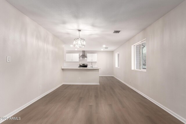 unfurnished living room with a chandelier, visible vents, baseboards, and dark wood-style flooring