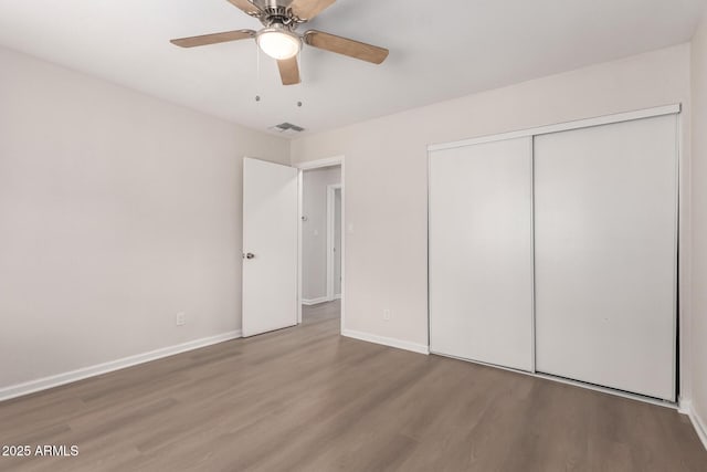 unfurnished bedroom with visible vents, baseboards, wood finished floors, a closet, and a ceiling fan