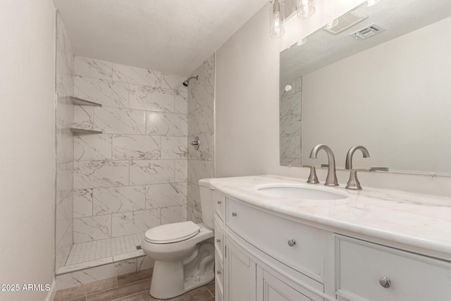 full bathroom featuring visible vents, tiled shower, toilet, and vanity