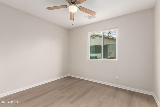 empty room with a ceiling fan, wood finished floors, visible vents, and baseboards