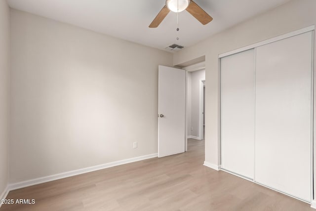 unfurnished bedroom featuring visible vents, a ceiling fan, a closet, light wood-style floors, and baseboards