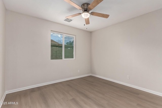 spare room featuring visible vents, baseboards, wood finished floors, and a ceiling fan