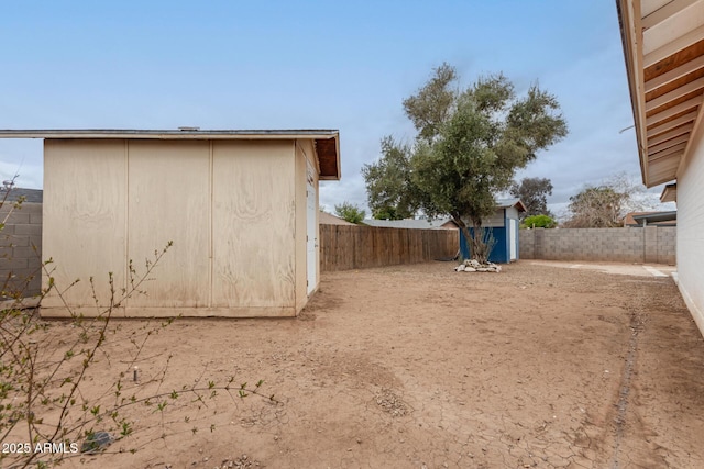 view of yard with an outdoor structure, a storage unit, and a fenced backyard