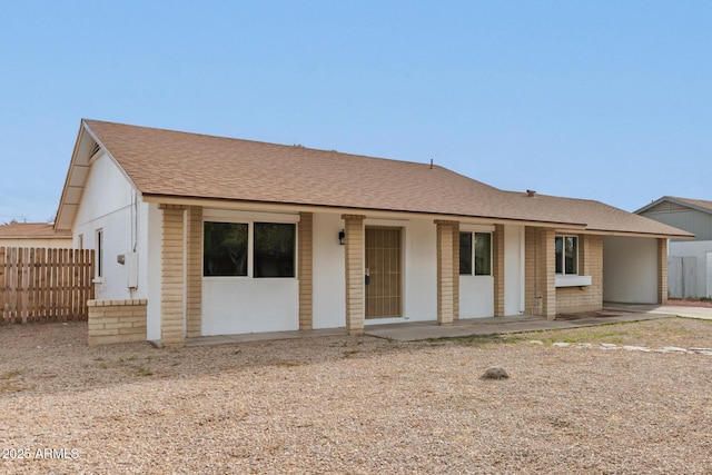 single story home featuring brick siding, covered porch, a shingled roof, and fence