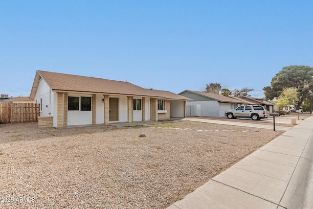 ranch-style home with brick siding, roof with shingles, and fence