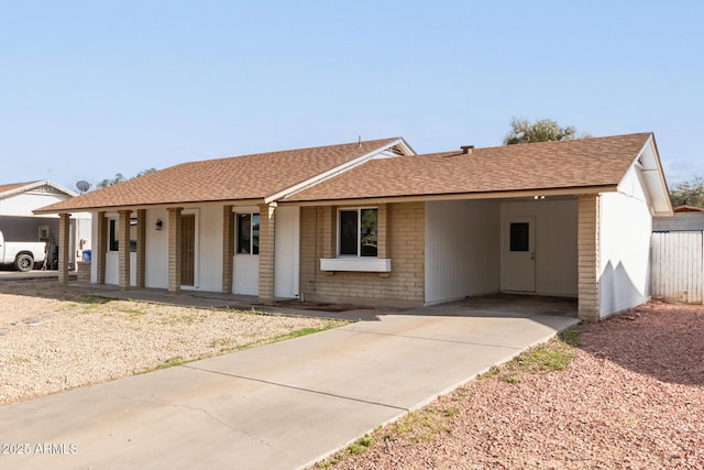 ranch-style home with brick siding, a porch, driveway, and roof with shingles