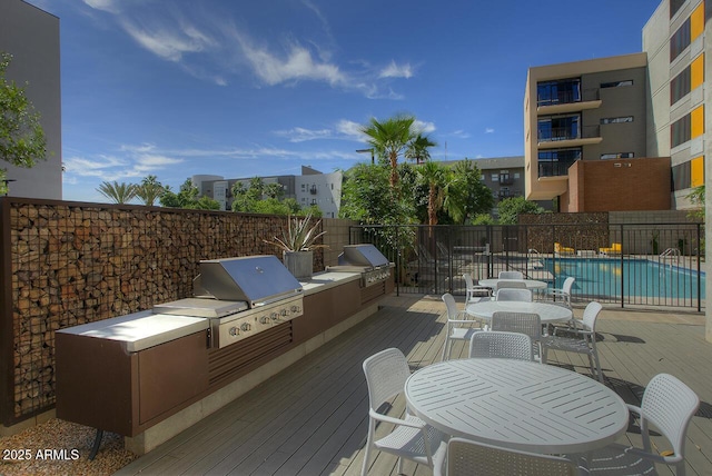 exterior space featuring a community pool, a patio area, exterior kitchen, and area for grilling