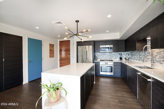 kitchen featuring appliances with stainless steel finishes, hanging light fixtures, sink, a kitchen island, and an inviting chandelier