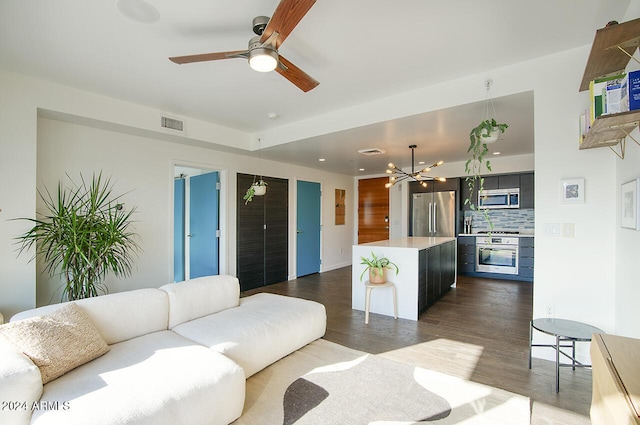 living room with ceiling fan with notable chandelier and dark hardwood / wood-style floors