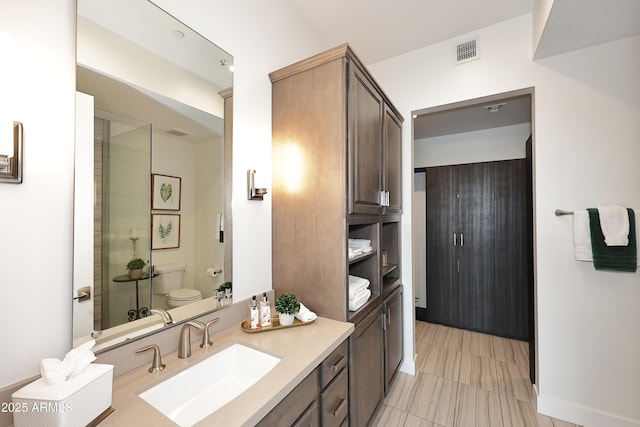 bathroom with vanity, toilet, and visible vents