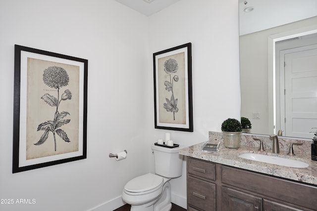 half bathroom with vanity, toilet, visible vents, and baseboards