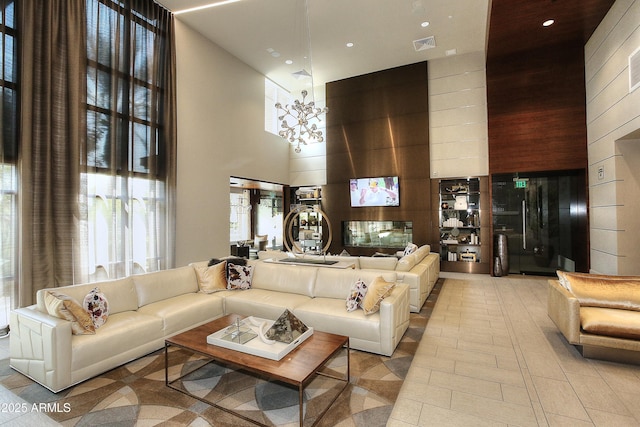 living area with wooden walls, visible vents, recessed lighting, a towering ceiling, and a chandelier